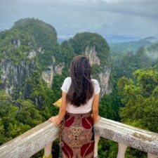woman in red and white floral dress standing on wooden bridge during daytime